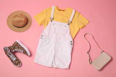 Pembe arka planda şık giysiler, spor ayakkabılar ve aksesuarlar, düz yatış.