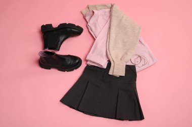 Pembe arka planda şık elbiseler, botlar ve aksesuarlar, düz yatış.