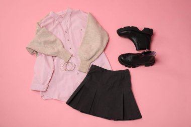 Pembe arka planda şık elbiseler, botlar ve aksesuarlar, düz yatış.