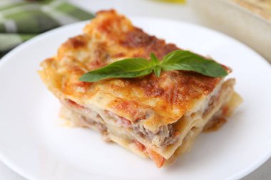 Lezzetli pişmiş lazanya tabağında fesleğen, yakın plan.