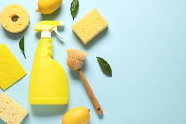 Açık mavi arka planda temizlik ürünleri, aletler ve limonlar, düz yatış. Metin için boşluk