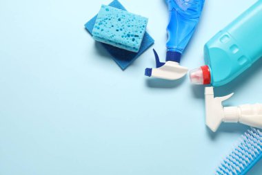Açık mavi arka planda temizlik ürünleri ve aletleri düz bir zeminde. Metin için boşluk