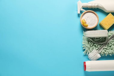 Açık mavi arka planda temizlik ürünleri ve aletleri düz bir zeminde. Metin için boşluk