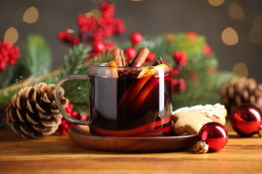 Baharatlı lezzetli bir bardak şarap ve ahşap masa üzerindeki Noel süsü bulanık ışıklara karşı, yakın plan.