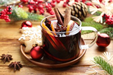 Baharatlı lezzetli şarap, portakal dilimleri ve ahşap masada Noel süsü, yakın plan.