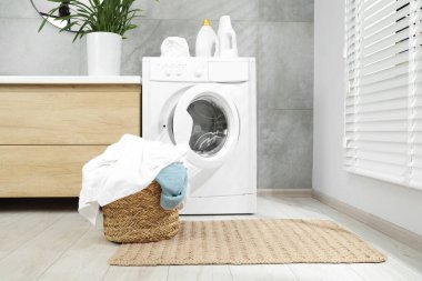 Banyoda yerde çamaşır dolu bir sepet.