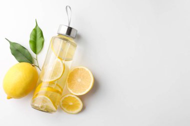 Şişe içinde limon suyu, beyaz arka planda taze meyve ve yapraklar, üst manzara. Metin için boşluk