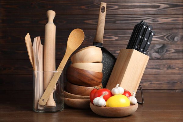 Dishware, cooking utensils with vegetables and lemon on wooden table