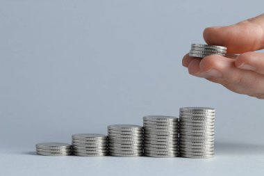 Maaş konsepti. Açık gri arkaplan üzerine bozuk para koyan kadın, yakın plan