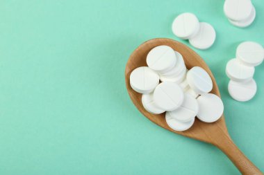 Turkuaz arka planda kaşıkta antibiyotik haplar, üst manzara. Metin için boşluk