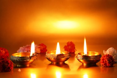 Diwali celebration. Diya lamps and beautiful flowers on golden background clipart