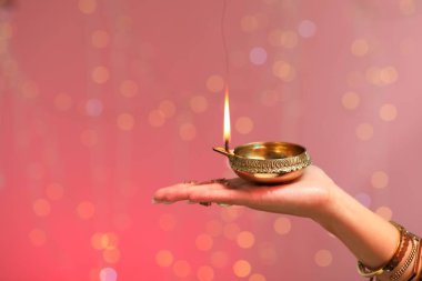 Diwali kutlaması. Elinde yanan diya lambası tutan bir kadın. Arka planda bulanık ışıklar var. Yakın plan. Metin için boşluk