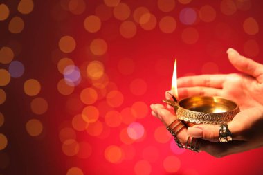 Diwali kutlaması. Kırmızı arka planda yanan, bulanık ışıkları olan bir kadın, yakın plan. Metin için boşluk