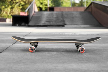 One modern skateboard with black griptape in skatepark clipart