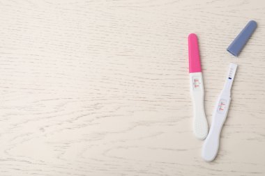 Beyaz ahşap masa üzerinde iki hamilelik testi. Metin için boşluk