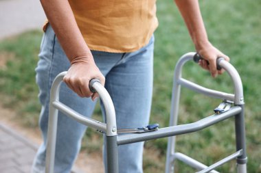 Senior woman with walking frame in park, closeup clipart