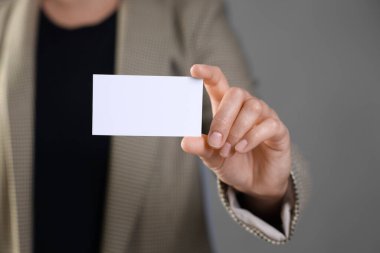 Gri arka planda boş kartviziti olan bir kadın, yakın plan. Tasarım için model