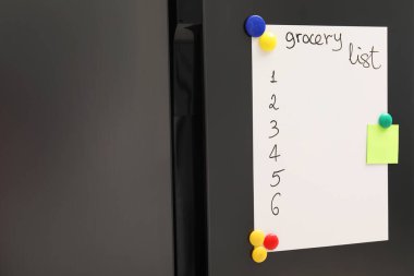 Alışveriş listesi ve mutfaktaki buzdolabının üzerine not olan manyetik tahta.