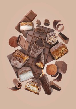 Pembe gri arka planda havada farklı çikolata ürünleri