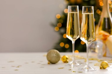 Gözlüklü şampanya ve beyaz ahşap masa üzerindeki Noel süsü bulanık ışıklara karşı, mesaj için yer. Bokeh etkisi