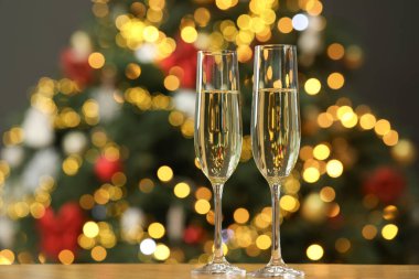 Ahşap masanın üzerinde, bulanık Noel ışıklarına karşı şampanya, mesaj için yer. Bokeh etkisi
