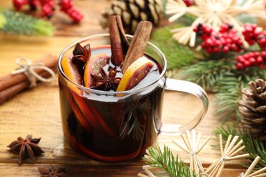 Baharatlı lezzetli şarap, portakal dilimleri ve ahşap masada Noel süsü, yakın plan.