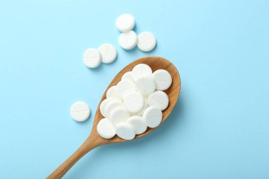 Antibiyotik haplar ve açık mavi arka planda kaşık, düz uzanma