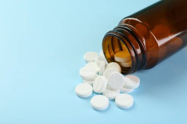Açık mavi arka planda bir şişe antibiyotik hapı, yakın plan. Metin için boşluk