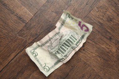 Tahta masanın üzerinde buruşuk bir dolar banknot, üst manzara.