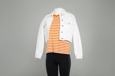 Açık gri arka planda şık giyimli kadın mankeni.