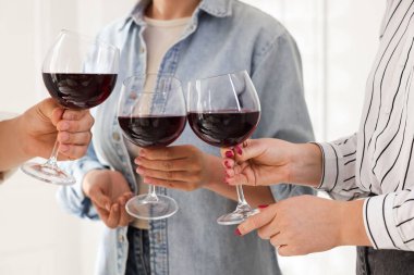 Kapalı mekanda kırmızı şarap kadehlerini tokuşturanlar.