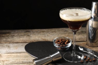 Bir bardak nefis espresso martini, jigger ve kahve çekirdekleri siyah arka planda, yakın plan. Metin için boşluk