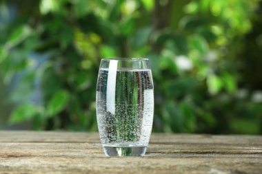 Dışarıdaki ahşap masada cam içinde soda.