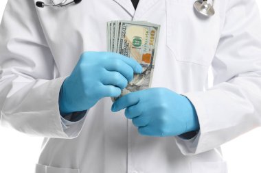 Yozlaşma konsepti. Doktor ceketine dolar banknotları koyuyor, beyaz arka planda, yakın plan.
