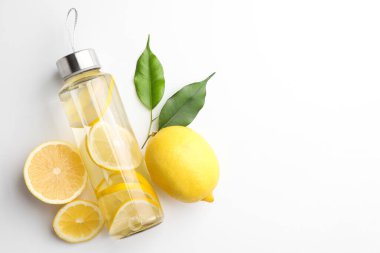 Şişe içinde limon suyu, beyaz arka planda taze meyve ve yapraklar, üst manzara. Metin için boşluk