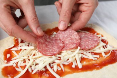 Calzone pizzası yapıyorum. Masada sosis dilimleyen kadın, yakın plan.