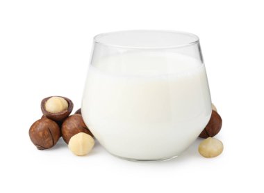 Beyaz üzerine izole edilmiş bir bardak Macadamia sütü ve fındık.