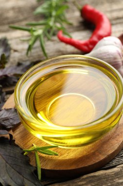 Kavanozda yağ, ahşap masada fesleğen ve biberiye, yakın plan.