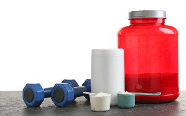 Beyaz arkaplana karşı gri desenli masadaki protein tozu ve dambıllar