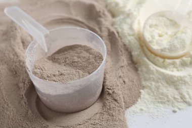 Beyaz arka planda protein tozları ve kepçeler, yakın plan