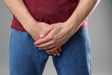 Cinsel yolla bulaşan hastalıklar. Gri arka planda semptomlardan muzdarip bir adam, yakın plan