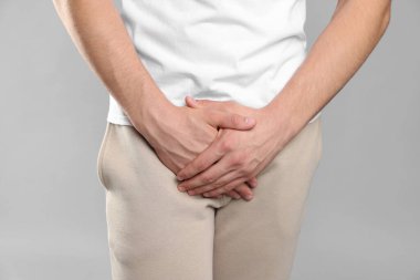 Cinsel yolla bulaşan hastalıklar. Gri arka planda semptomlardan muzdarip bir adam, yakın plan