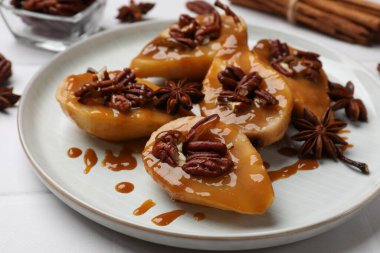 Delicious pears with caramel sauce, pecan nuts and anise stars on white table, closeup clipart