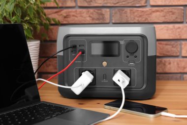İçerideki ahşap masada taşınabilir elektrik santralinden şarj edilen cihazlar