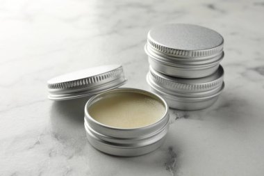 Lip balms on white marble table, closeup. Cosmetic product clipart