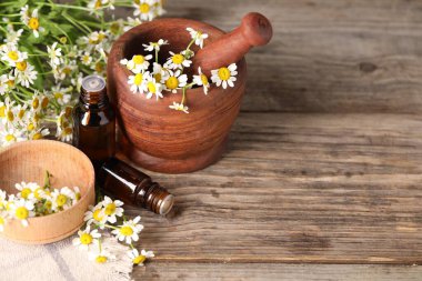 Gerekli yağ şişeleri, papatya çiçekleri, ahşap masa üzerinde havan topu ve tokmak. Metin için boşluk