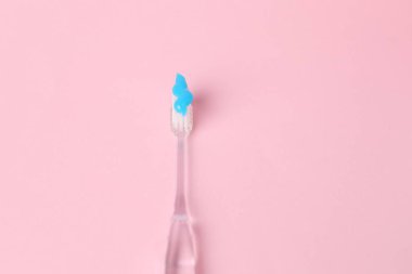 Pembe arka planda diş macunu olan bir diş fırçası.