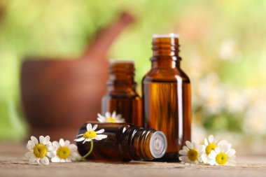 Ahşap masada gerekli yağ ve papatya çiçekleri, yakın plan.