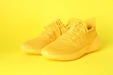 Sarı arka planda şık bir çift spor ayakkabı.