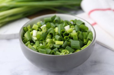 Doğranmış yeşil soğan beyaz masada, yakın plan.